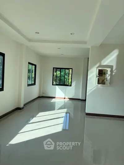 Spacious sunlit room with large windows and glossy floors, perfect for modern living.