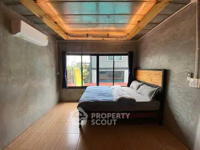 Modern industrial-style bedroom with large window and cozy bed.