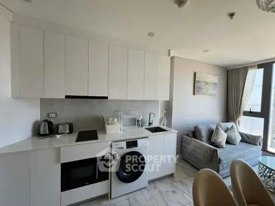 Modern kitchen and living room with sleek appliances and cozy seating area.