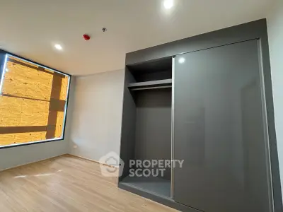 Spacious bedroom with modern built-in wardrobe and large window.
