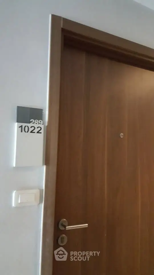 Modern apartment entrance with sleek wooden door and room number 1022, ideal for urban living.