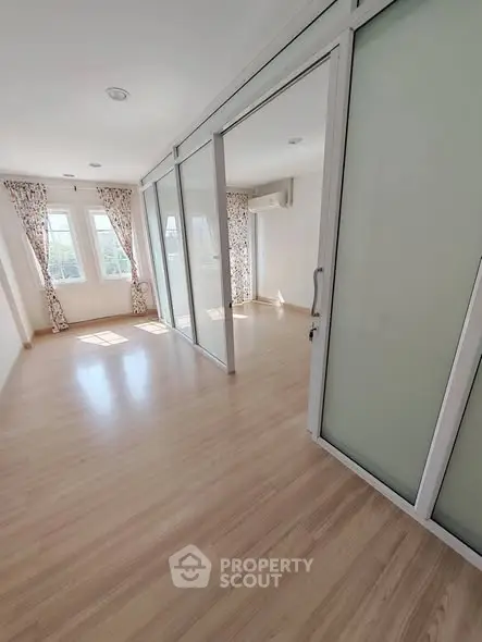 Spacious sunlit room with sliding glass doors and wooden flooring