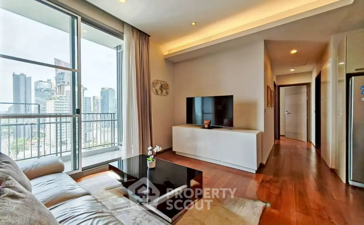 Modern living room with city view, sleek furniture, and natural light in high-rise apartment.