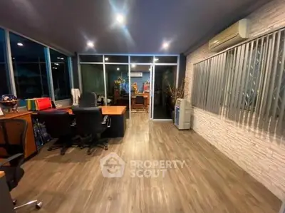 Spacious modern office with sleek wooden flooring and large windows for natural light.