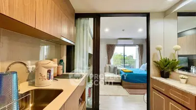 Modern studio apartment with seamless open layout connecting a fully equipped kitchen to a cozy bedroom area, featuring large windows for ample natural light.