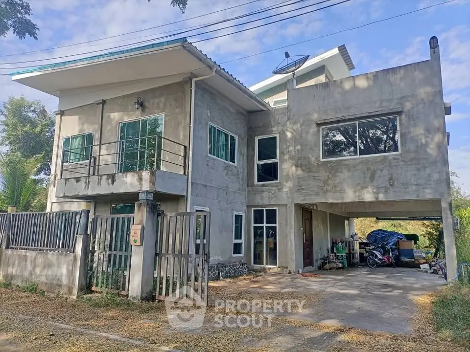 Modern two-story concrete house with large windows and spacious driveway
