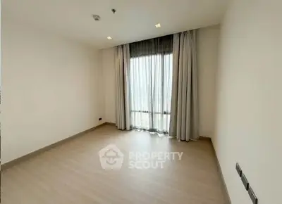 Spacious empty bedroom with large window and elegant curtains in modern apartment.