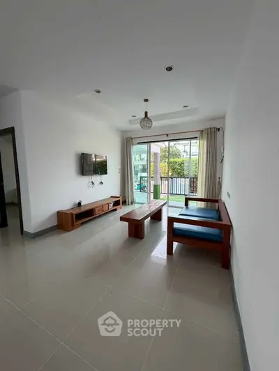 Spacious living room with modern furniture and large windows opening to a balcony.