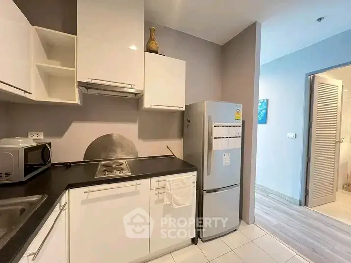Modern kitchen with sleek white cabinets and stainless steel appliances in a stylish apartment.