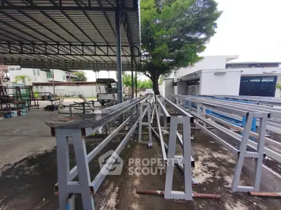 Industrial outdoor area with metal structures and a tree, showcasing construction elements.