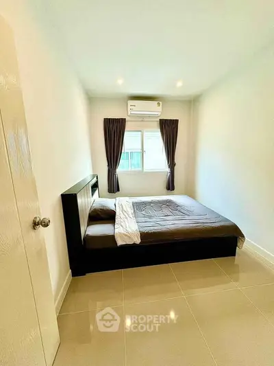 Modern bedroom with sleek design, featuring a comfortable bed and natural light from a window.