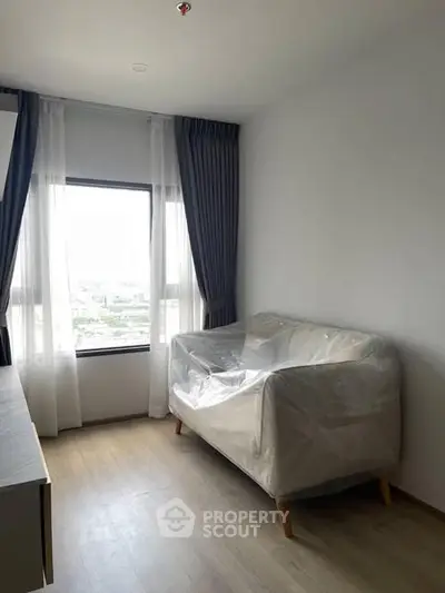 Bright room with large window and sofa, ideal for cozy living space.