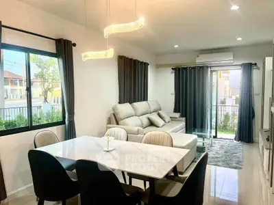 Modern living room with elegant dining area and large windows offering natural light.