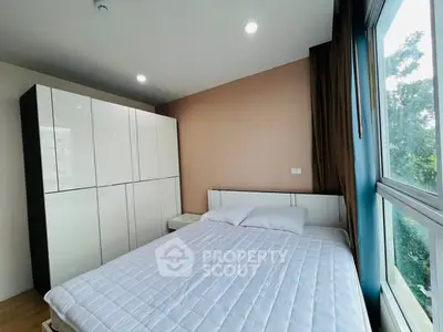 Bright bedroom with large window and modern wardrobe, offering serene views and ample storage space.