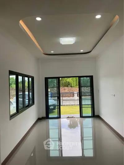 Spacious modern living room with large windows and glossy floor, offering a serene garden view.