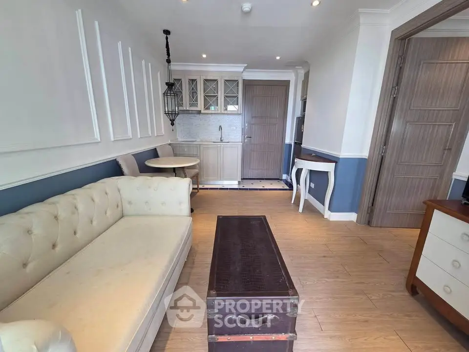 Charming living room with elegant decor and compact kitchen in open layout, featuring stylish furniture and soft lighting.