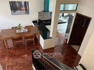Spacious dining area with wooden flooring and modern kitchen in open layout design.