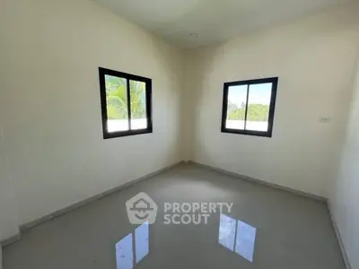 Spacious empty room with glossy floor and large windows offering natural light.