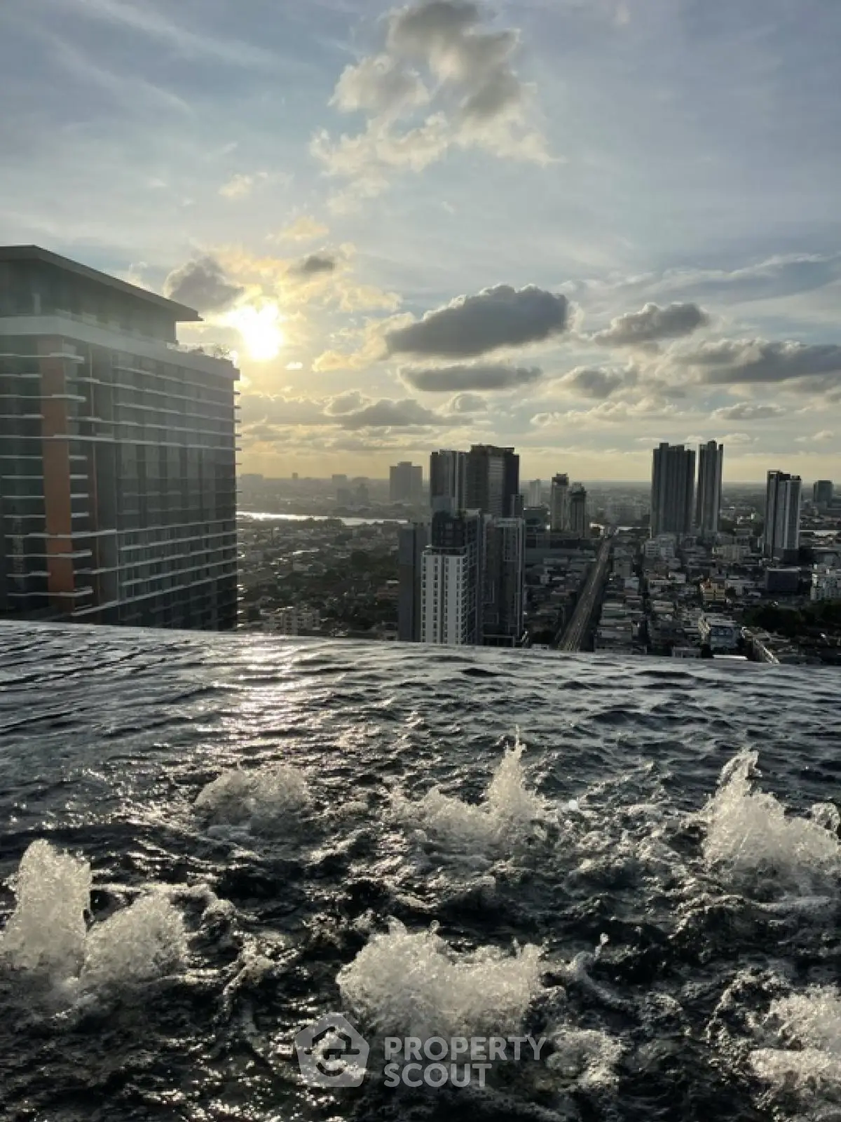 Stunning rooftop infinity pool with breathtaking city skyline view at sunset.