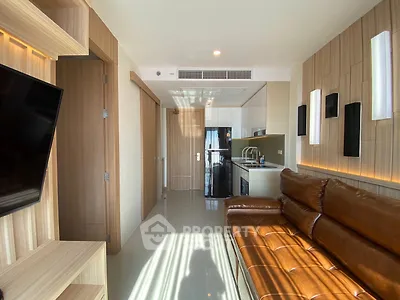 Modern living room with sleek design and open kitchen layout, featuring leather sofa and stylish lighting.