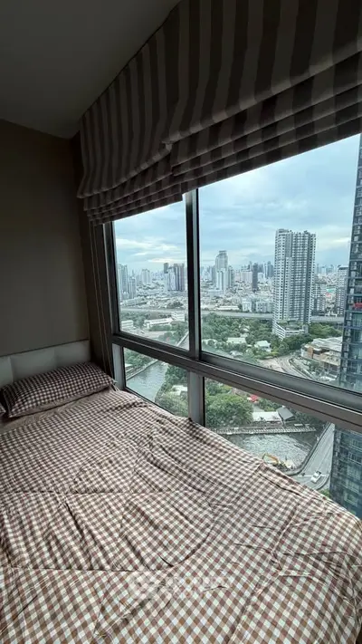 Stunning city view from a high-rise bedroom with large windows and cozy bedding.