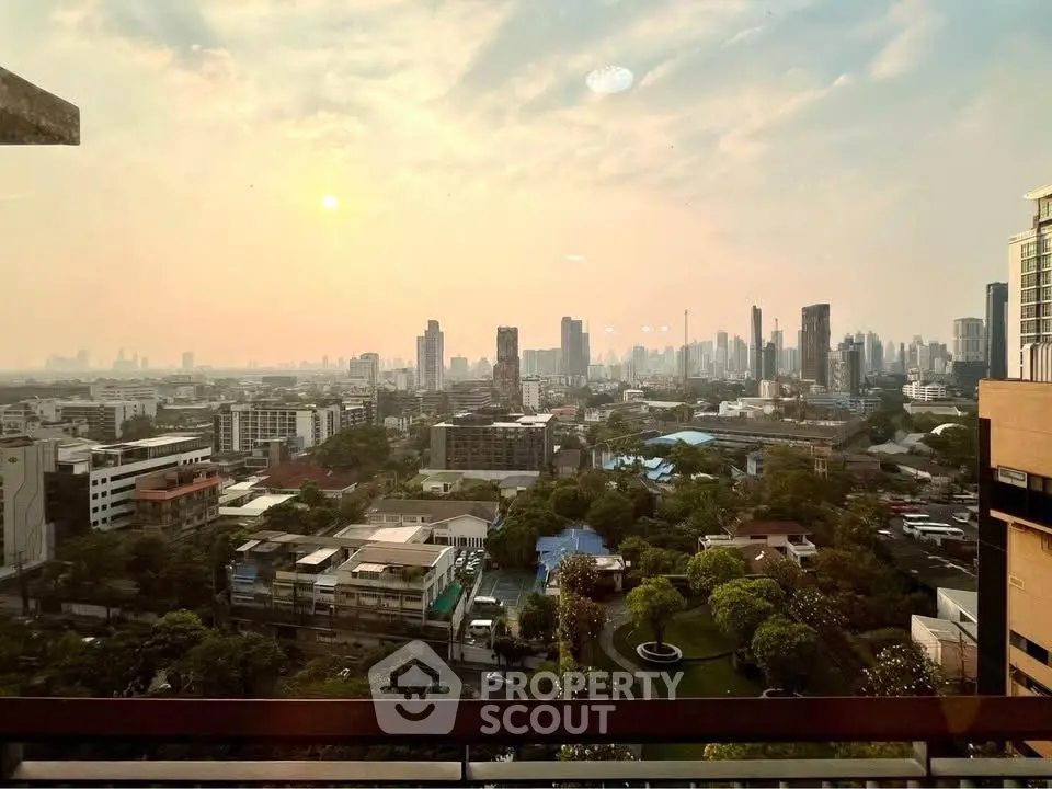 Stunning cityscape view from high-rise building at sunset, showcasing urban skyline and lush greenery.
