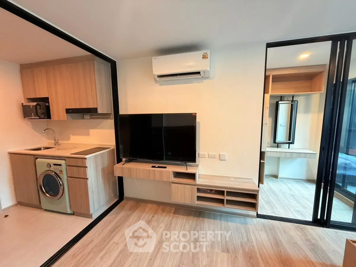 Modern studio apartment with open kitchen and living area, featuring sleek appliances and stylish decor.