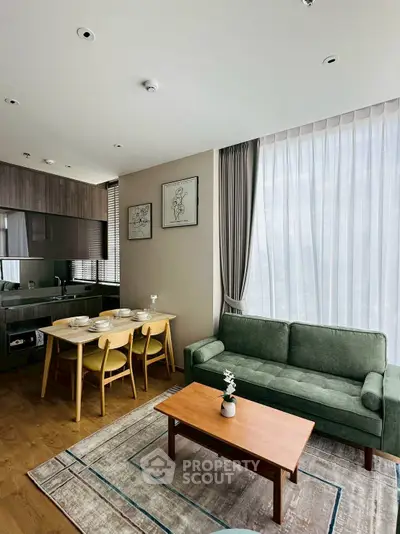 Modern living room with open kitchen, stylish furniture, and large windows for natural light.