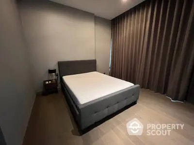 Spacious bedroom with modern design, featuring a large bed with a stylish headboard, elegant dark curtains, and wooden flooring.