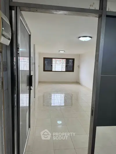 Spacious empty room with tiled flooring and large windows, ideal for customization.