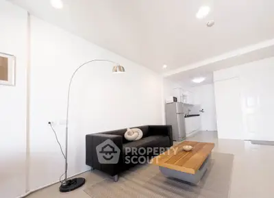 Modern living room with sleek black sofa and stylish kitchen in open layout apartment.
