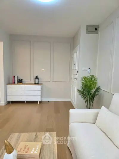 Modern living room with elegant decor and wooden flooring, featuring a cozy white sofa and stylish storage unit.