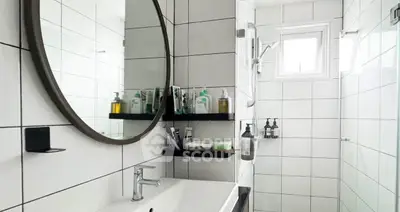 Modern bathroom with sleek white tiles and round mirror
