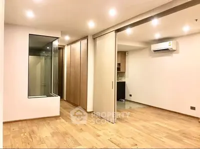 Spacious modern living area with wooden flooring and sliding doors in a contemporary apartment.