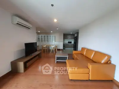 Spacious modern living room with orange sofa and open kitchen layout, perfect for contemporary living.