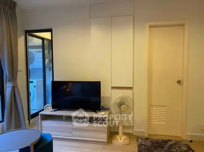 Modern living room with TV, fan, and stylish decor in a cozy apartment setting.