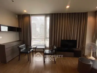 Modern living room with city view, featuring sleek furniture and floor-to-ceiling windows.