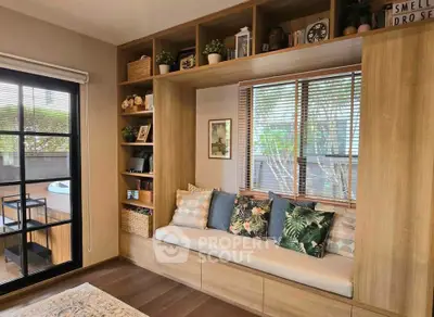Charming living room with built-in seating and large window overlooking lush greenery.