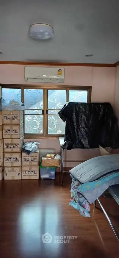 Cozy room with wooden flooring, air conditioning, and ample storage space.