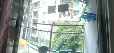 Charming balcony view with lush greenery and modern building backdrop, perfect for relaxation.