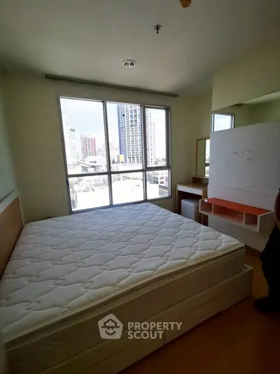 Bright bedroom with large window and city view, featuring a comfortable bed and modern furniture.