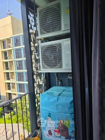 Outdoor balcony with air conditioning units and decorative cover, overlooking modern building.