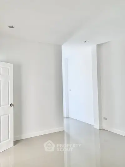 Spacious empty room with glossy tiled floor and white walls, ready for customization.
