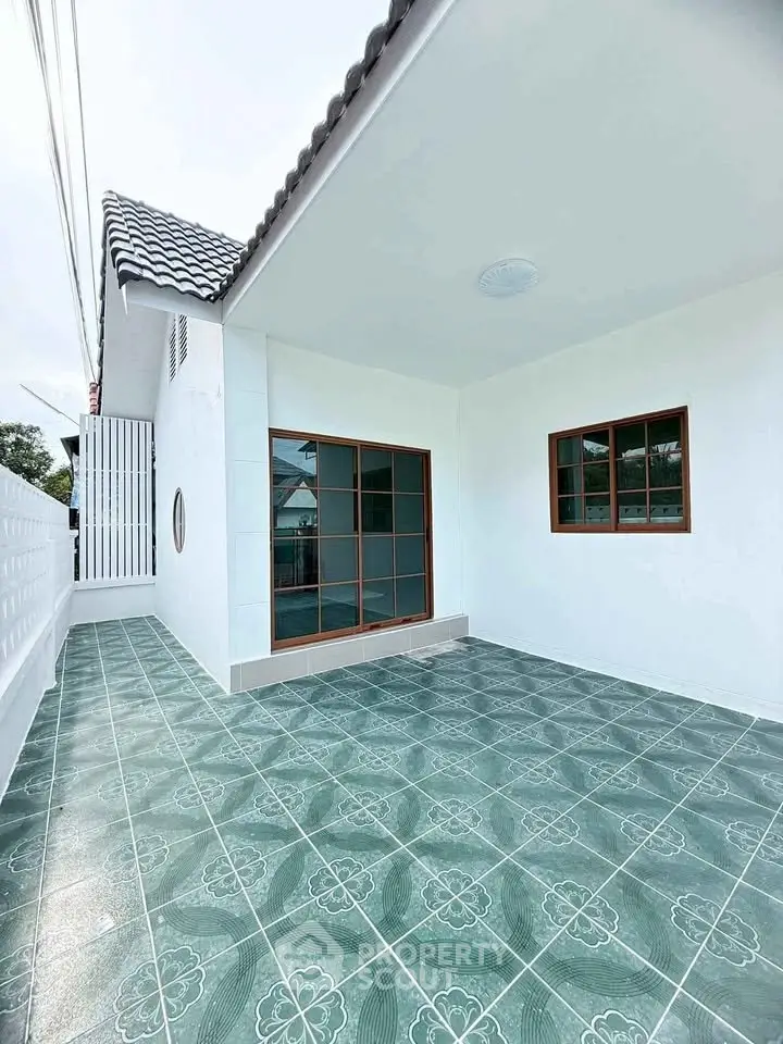 Charming single-story home with tiled patio and modern windows, perfect for outdoor relaxation.