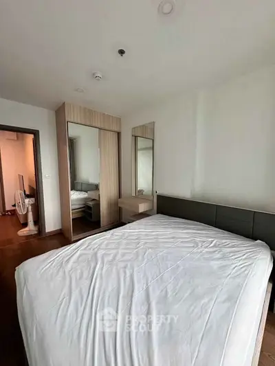 Modern bedroom with stylish mirrored wardrobe and cozy bed in a contemporary apartment.