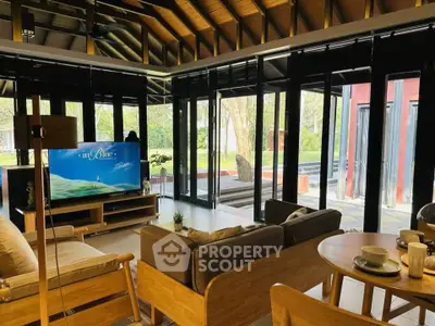 Spacious living room with modern decor and large windows overlooking a lush garden.