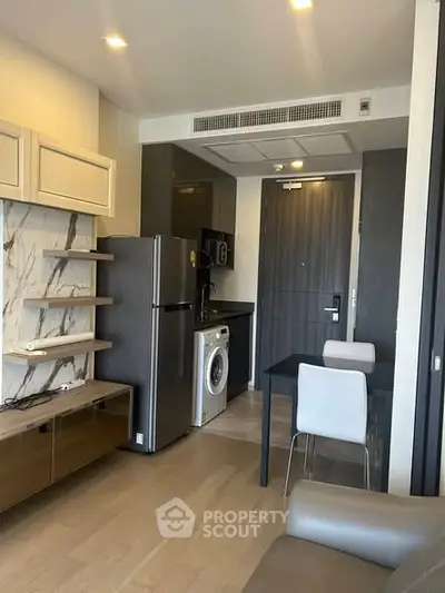 Modern apartment interior with kitchen and dining area, featuring sleek appliances and stylish decor.