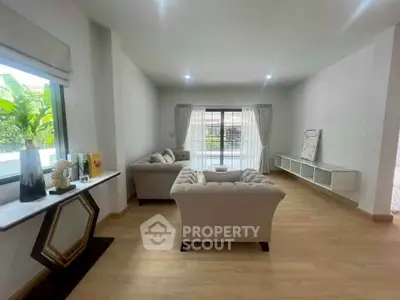 Spacious living room with elegant sofas and large windows offering natural light.