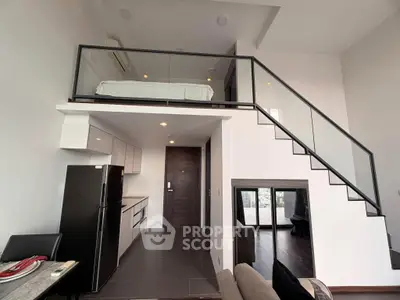 Modern loft apartment with sleek kitchen and mezzanine bedroom, featuring stylish glass railing and high ceilings.