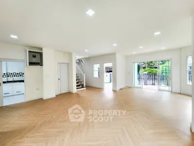 Spacious open-plan living room with modern flooring and large windows leading to garden.